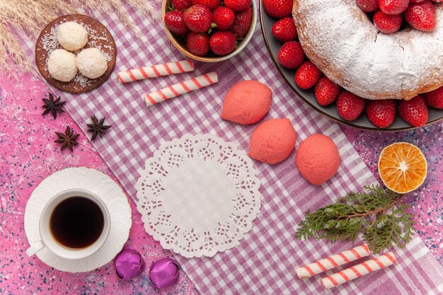 Vue de dessus gâteau aux fraises tarte en poudre de sucre avec des gâteaux roses et du thé sur rose