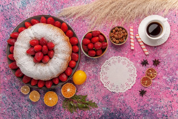 Vue de dessus gâteau aux fraises tarte en poudre de sucre avec tasse de thé sur rose