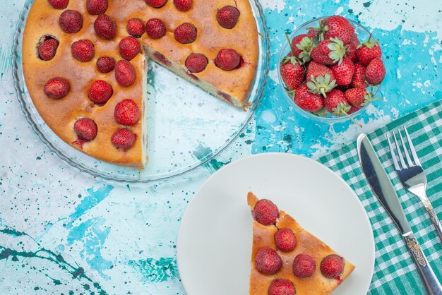 Vue de dessus gâteau aux fraises en tranches et délicieux gâteau entier avec des fraises rouges fraîches sur le bureau bleu vif gâteau aux fruits de baies cuire