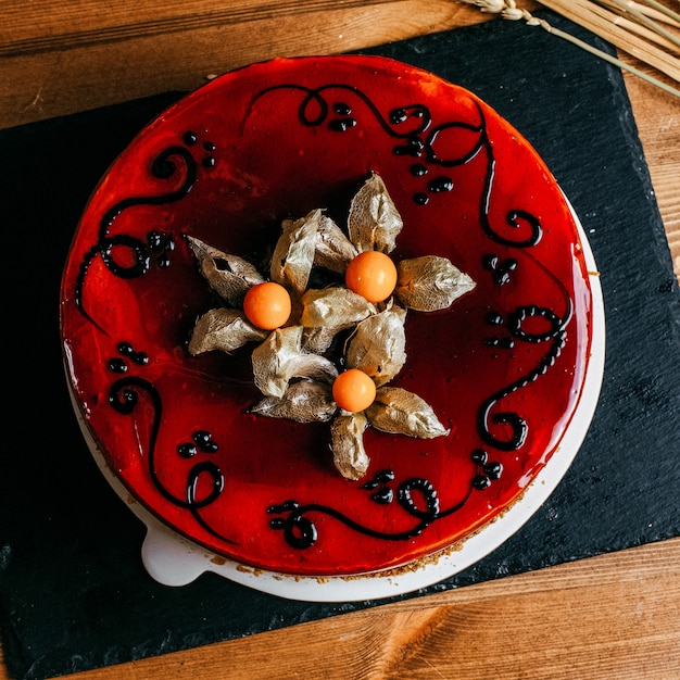 Une vue de dessus gâteau aux fruits avec de la crème syrop rouge décoré rond à l'intérieur de la plaque blanche