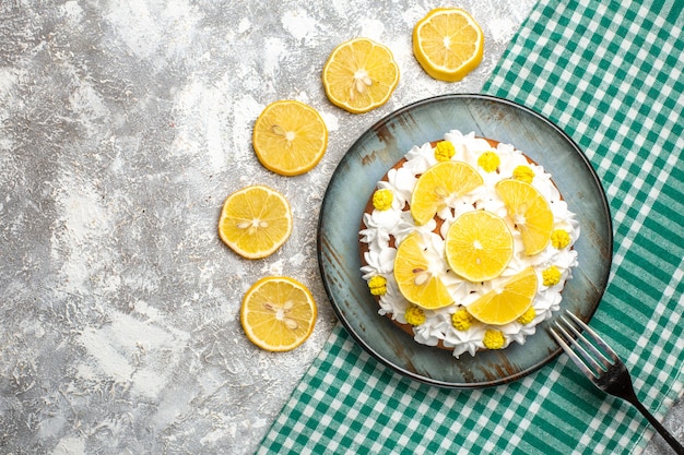 Photo gratuite vue de dessus gâteau avec crème pâtissière et fourchette au citron sur plateau sur nappe à carreaux blanc vert