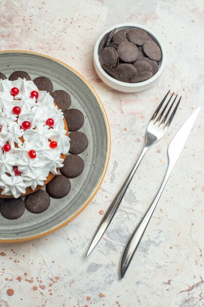 Vue de dessus gâteau avec crème pâtissière sur plaque ovale chocolat dans un bol fourchette et couteau à dîner