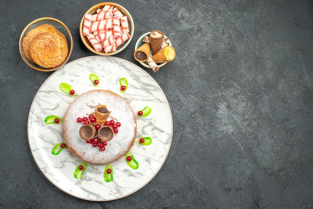 Vue de dessus un gâteau un gâteau appétissant avec des baies bols de biscuits bonbons colorés gaufres