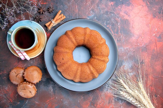 Vue de dessus un gâteau une tasse de thé assiette bleue de gâteaux cupcakes cannelle anis étoilé épis de blé