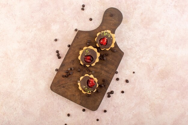 Une vue de dessus des gâteaux au chocolat sur le bureau en bois et table rose