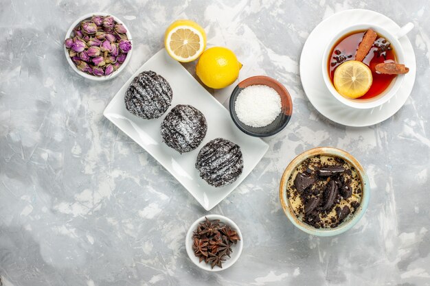 Vue de dessus des gâteaux au chocolat avec du citron et du thé sur une surface blanche