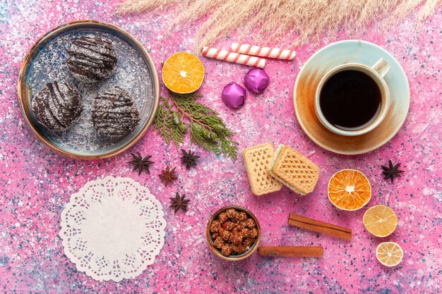 Vue de dessus des gâteaux au chocolat avec des gaufres et une tasse de thé sur rose