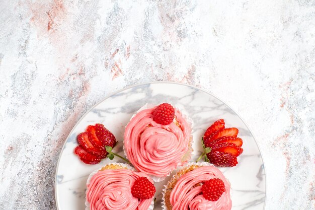 Vue de dessus des gâteaux aux fraises roses avec des baies fraîches sur une surface blanche