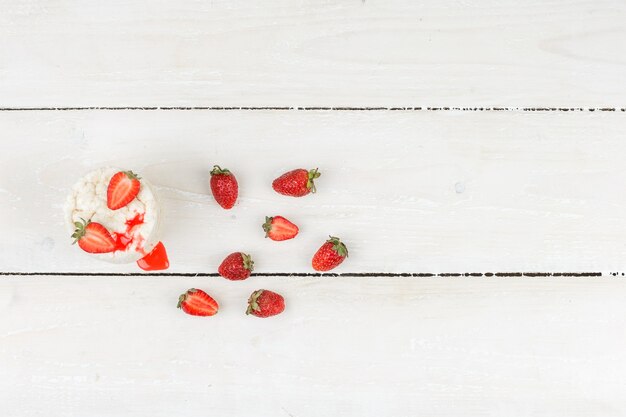 Vue de dessus des gâteaux de riz blanc avec des fraises sur la surface de la planche de bois blanc. horizontal