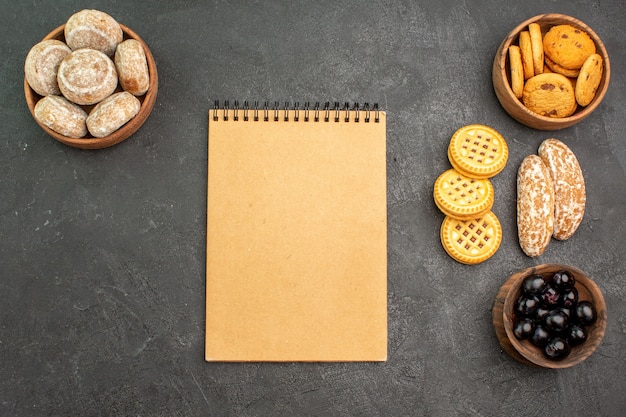 Vue de dessus des gâteaux sucrés avec des biscuits et des olives sur un gâteau de tartes sucrées de surface sombre