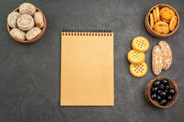 Vue de dessus des gâteaux sucrés avec des biscuits et des olives sur un gâteau de tartes sucrées de surface sombre