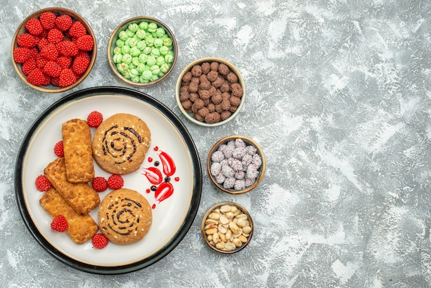 Vue de dessus des gâteaux sucrés avec des bonbons sur fond blanc gâteau biscuit sucré cookie au sucre