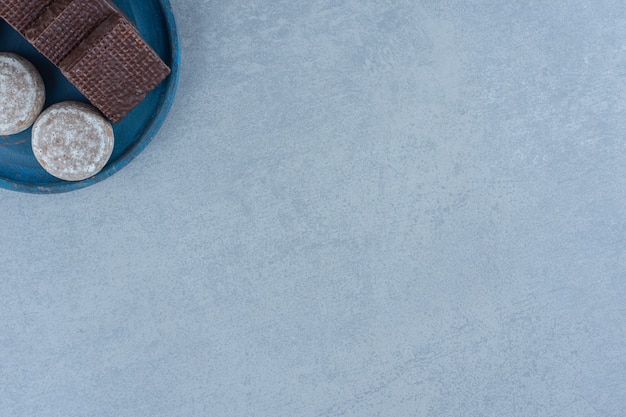 Vue de dessus des gaufrettes au chocolat avec cookie sur une plaque en bois bleue.