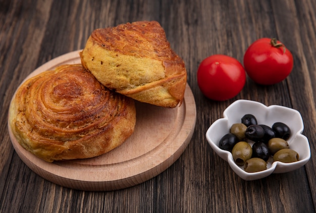 Vue de dessus des gogals sur une planche de cuisine en bois avec des olives sur un bol et des tomates fraîches isolés sur un fond en bois