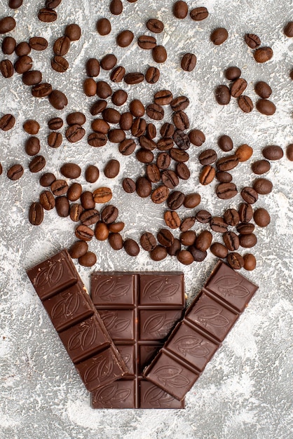 Vue de dessus des graines de café brun avec des barres de chocolat sur une surface blanche