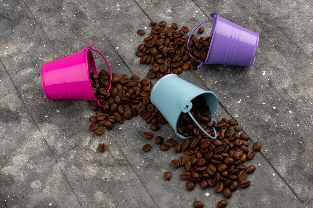 Vue de dessus des graines de café brun à l'intérieur de pots multicolores sur le gris en bois rustique