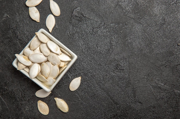 Vue de dessus des graines de citrouille fraîches sur la photo d'obscurité de granule de graine de fond sombre