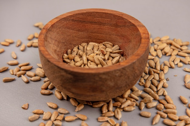 Vue de dessus des graines de tournesol décortiquées grillées sur un bol en bois avec des graines décortiquées isolées
