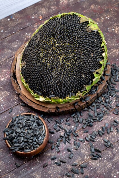 Une vue de dessus des graines de tournesol noires fraîches et savoureuses sur l'huile de collation de graines de tournesol grain de bureau brun