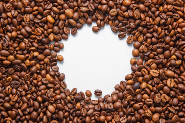 Vue de dessus des grains de café dans le trou au centre sur fond blanc. horizontal
