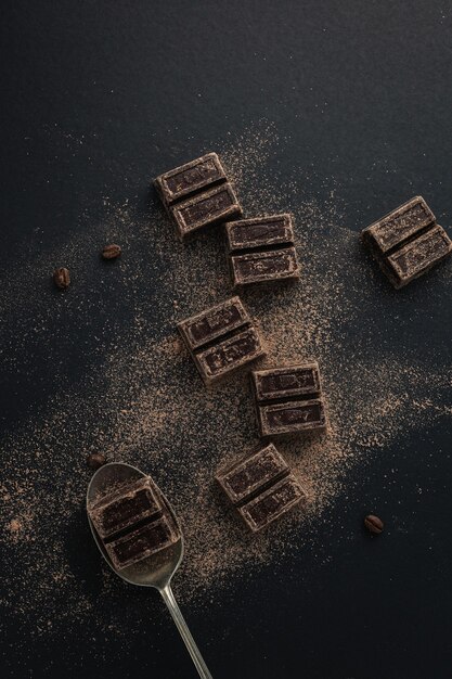 Vue de dessus des grains de café et des morceaux de chocolat noir saupoudrés de poudre de cacao