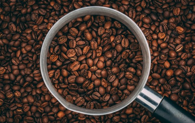 Vue de dessus des grains de café torréfiés dans une tasse en acier