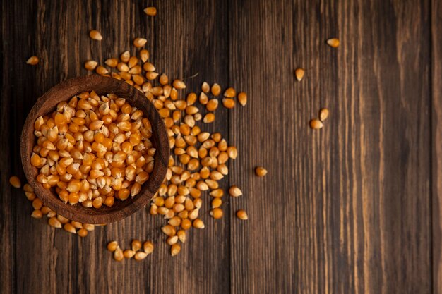 Vue de dessus des grains de maïs frais biologiques sur un bol en bois avec des grains de maïs isolé sur une table en bois avec espace copie