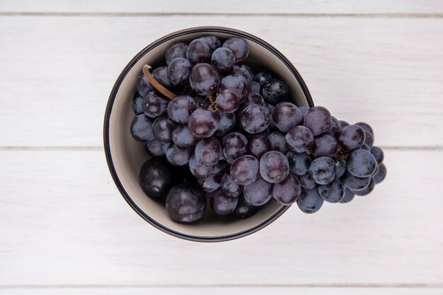 Vue de dessus grappe de raisin noir dans un bol sur fond blanc