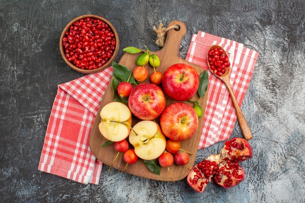 Vue de dessus grenade graines de grenade cuillère la planche de pommes cerises sur la nappe