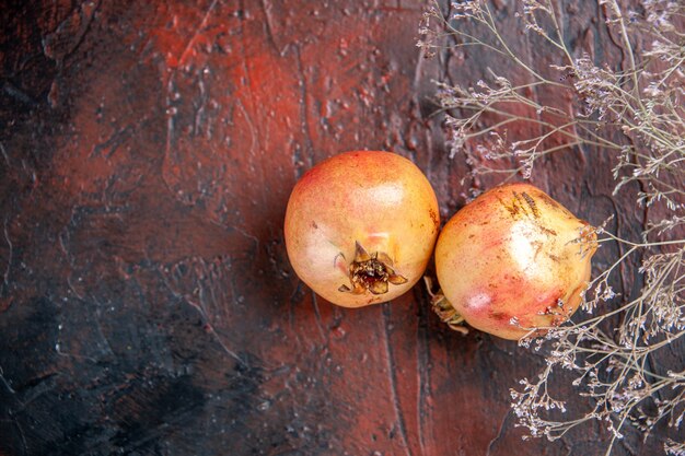 Vue de dessus des grenades fraîches branche de fleurs sauvages séchées sur fond de bois rouge foncé