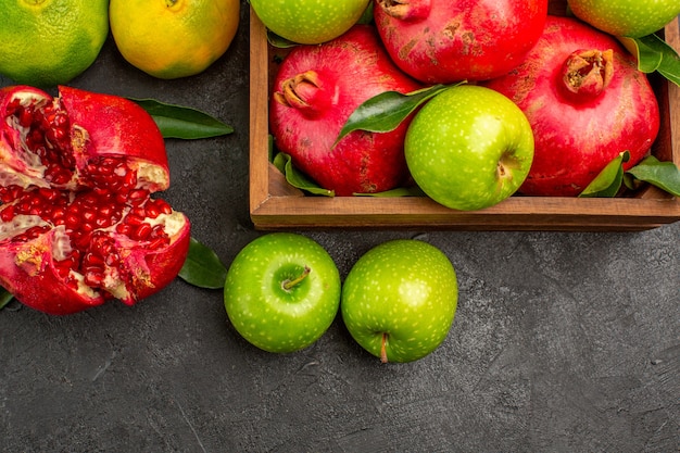 Vue de dessus des grenades fraîches avec des mandarines et des pommes sur les fruits mûrs de couleur de surface sombre