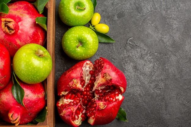 Photo gratuite vue de dessus des grenades fraîches avec des pommes vertes sur la couleur des fruits mûrs de surface sombre