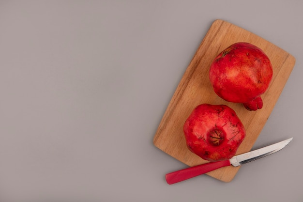 Vue de dessus des grenades rouges fraîches sur une planche de cuisine en bois avec couteau avec espace copie