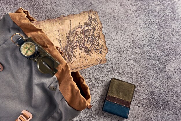 Vue de dessus gros plan d'une boussole placée sur un tissu coloré à côté d'une ancienne carte et d'un portefeuille
