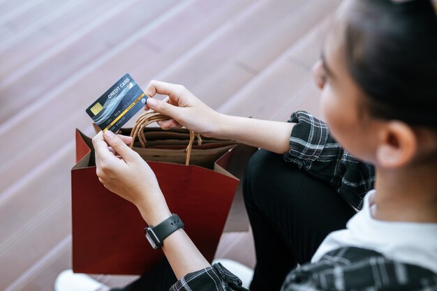 Vue de dessus, gros plan sur la main d'une jeune femme tenant une carte de crédit à la main avec un sac à provisions