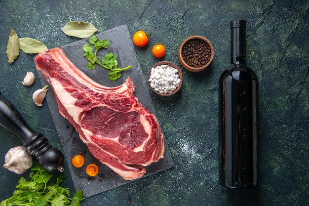 Vue de dessus grosse tranche de viande viande crue avec du poivre et des verts sur une surface sombre