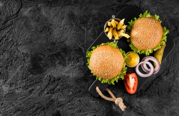 Vue de dessus des hamburgers et des frites sur une planche à découper avec cornichons et copy-space