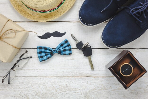 Vue de dessus Happy Father day on rustic wooden background. accessoires avec montre, moustache, cravate vintage, stylo, cadeau, clé automobile, chaussures et chapeau.