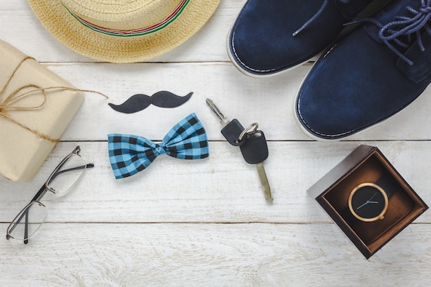 Vue de dessus Happy Father day on rustic wooden background. accessoires avec montre, moustache, cravate vintage, stylo, cadeau, clé automobile, chaussures et chapeau.