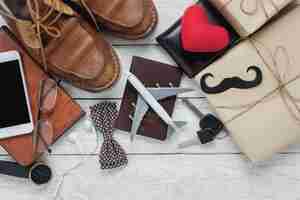 Photo gratuite vue de dessus happy father day with travel concept. avion et passeport sur fond de bois rustique. accessoires avec coeur rouge, moustache, cravate vintage, stylo, cadeau, téléphone portable blanc, chaussures, écouteurs, horloge et cahier.