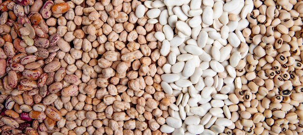 Vue de dessus des haricots blancs et colorés avec des pois sur une surface en bois brune