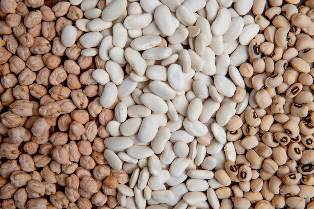 Vue de dessus des haricots blancs et colorés avec des pois sur une surface en bois brune