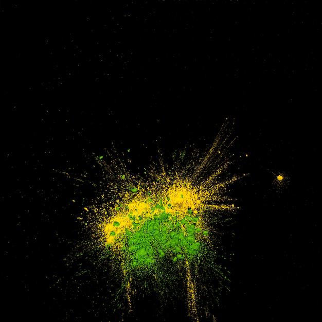 Vue de dessus de holi jaune et vert poudre colorée sur fond noir