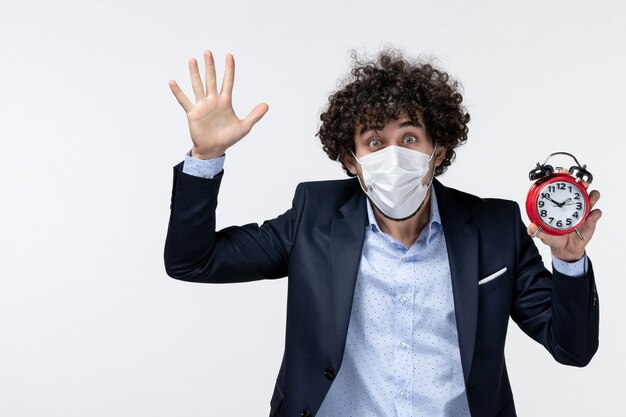 Vue de dessus d'un homme d'affaires émotionnel en costume et portant son masque tenant une horloge montrant cinq