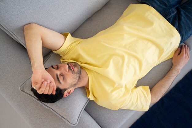 Vue de dessus homme fatigué dormant sur le canapé