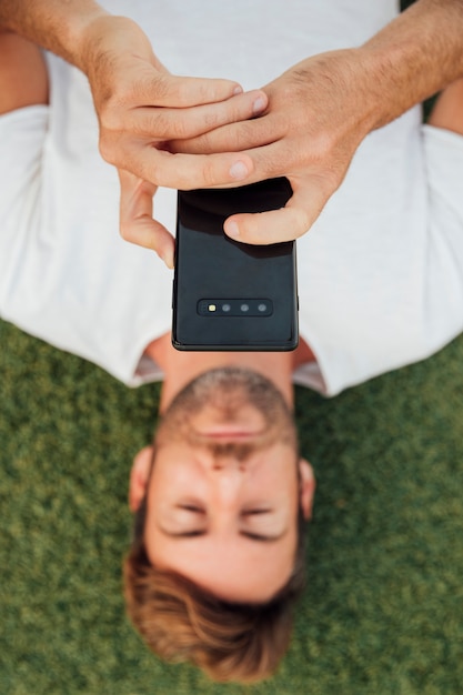 Vue de dessus homme sur l'herbe tenant un téléphone portable