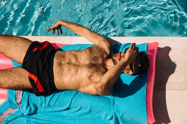 Vue de dessus de l&#39;homme relaxant à côté de la piscine