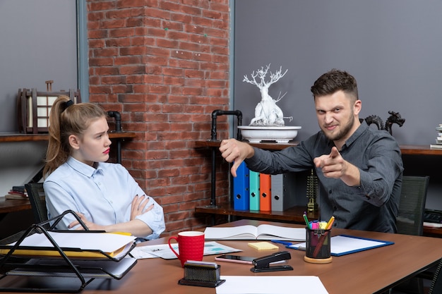 Photo gratuite vue de dessus d'une jeune équipe de bureau confuse assise à la table pour discuter d'un problème important au bureau