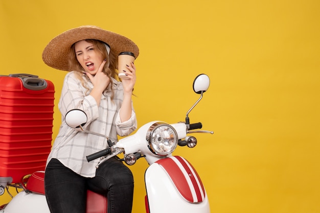 Vue de dessus d'une jeune femme ambitieuse portant un chapeau et assis sur une moto et tenant un café