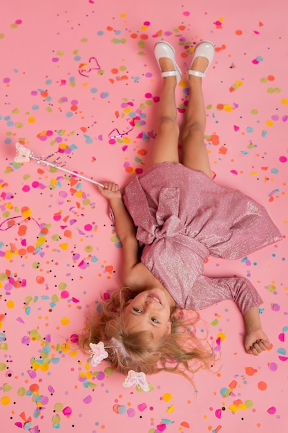 Vue de dessus de la jeune fille en costume de fée avec des confettis et baguette